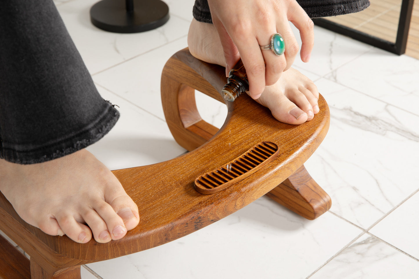 woman dropping essential oils into natural wood diffuser